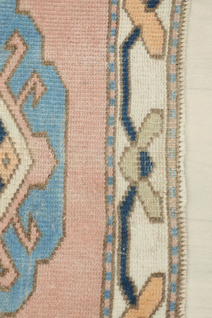 Close-up of the ivory border with geometric patterns and the pink central field.