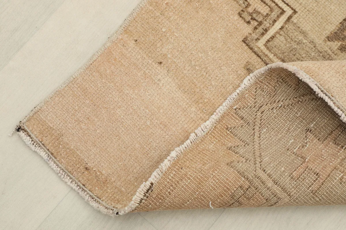 Corner of the rug folded to show the cotton foundation and reverse side
