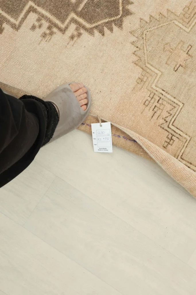 Foot next to the rug showing its thickness and a product tag