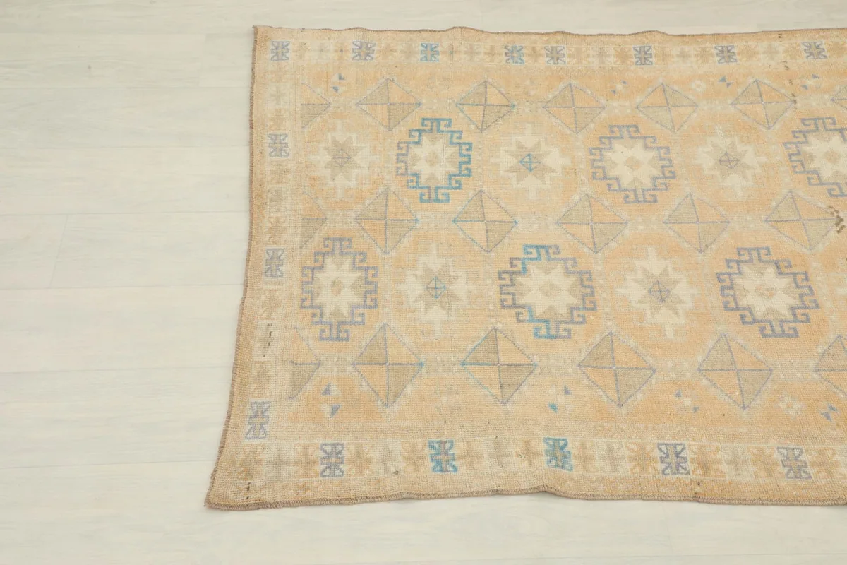 Angled view of the lower section of the vintage rug, highlighting blue geometric patterns