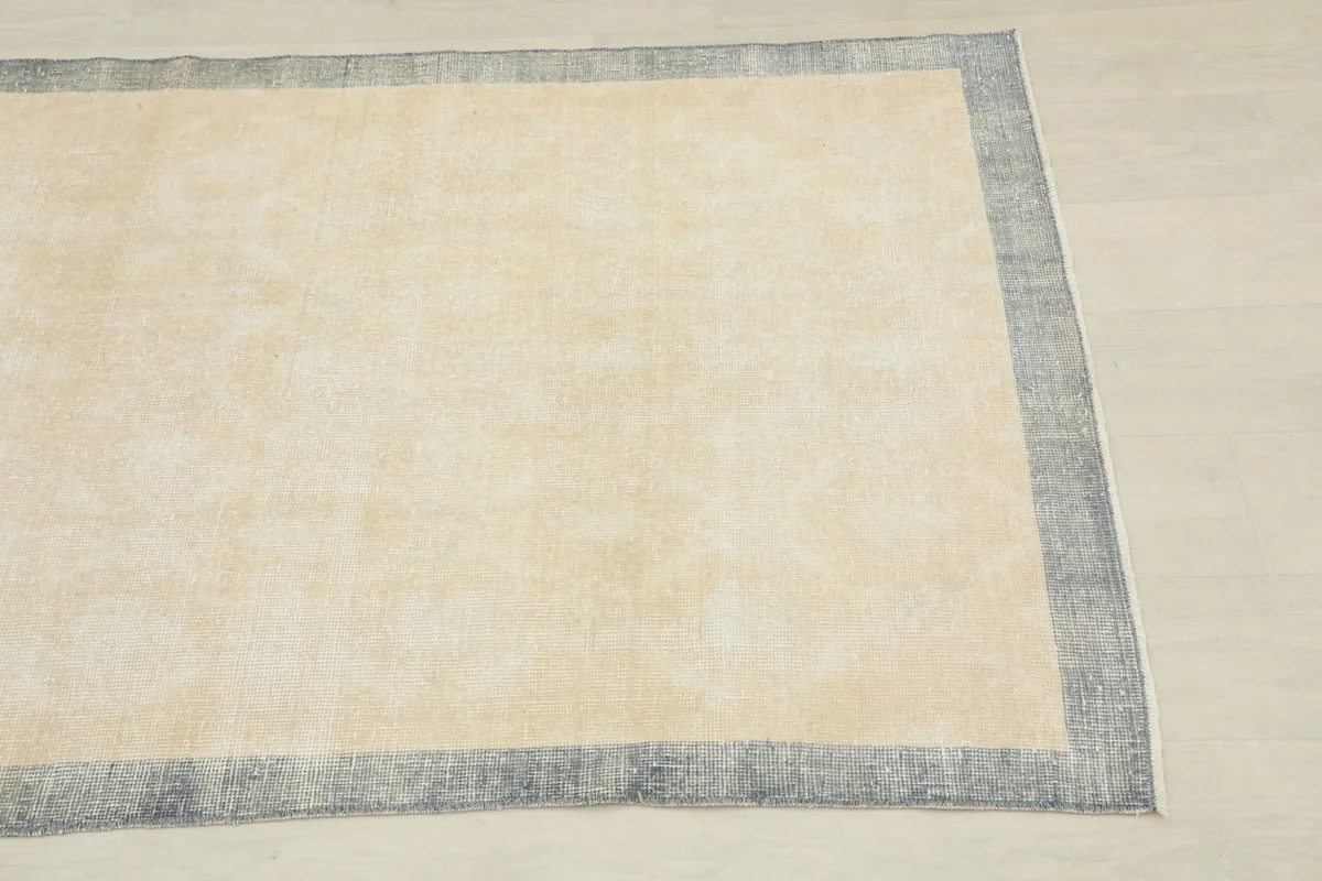 Close-up angled view of a corner of the cream and gray vintage rug