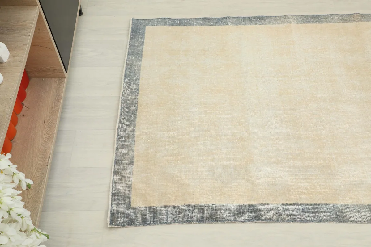 Angled view showing the cream field and gray border of the hand-knotted rug