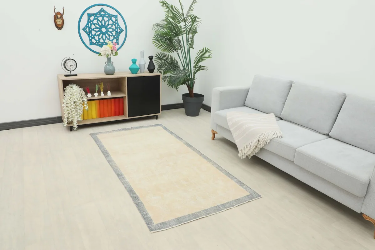 Cream and gray vintage rug placed in a living room setting with a sofa and cabinet