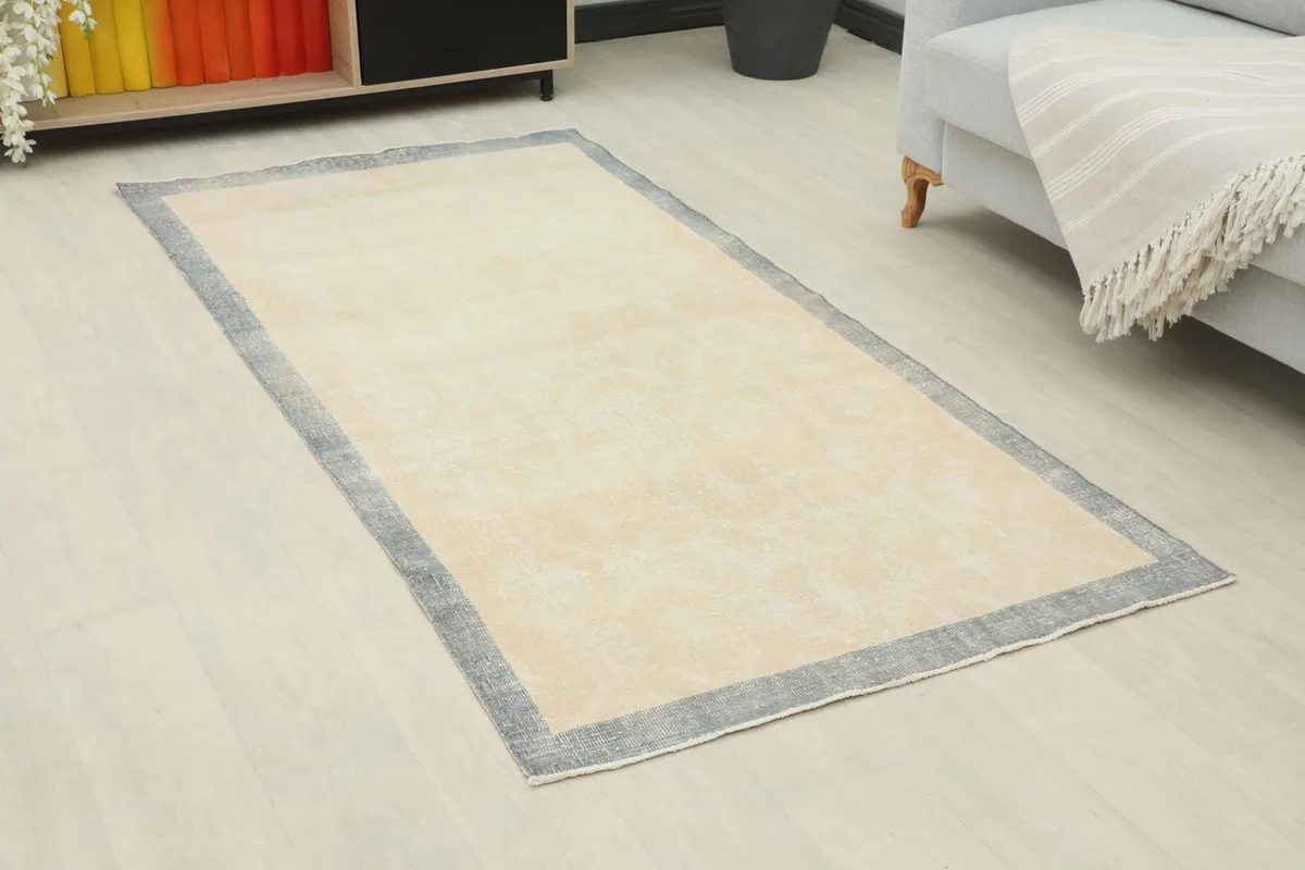 Angled view of the cream and gray vintage rug on a light floor in a home setting