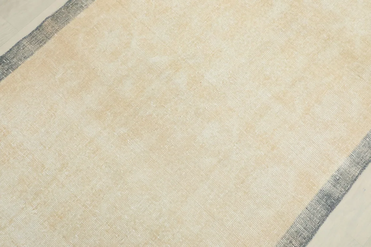Detail view of the cream field of the vintage wool rug, showing subtle texture