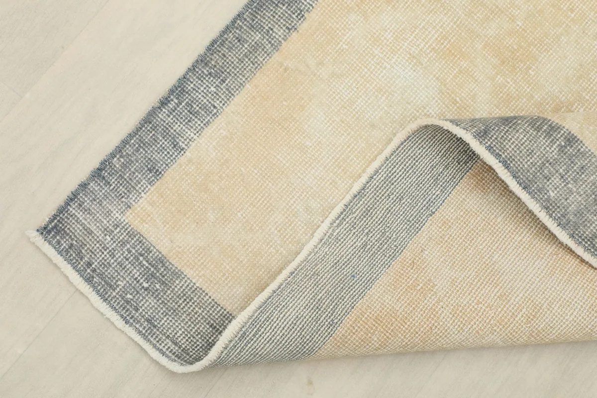 Corner of the vintage rug folded to show the cotton foundation and wool pile