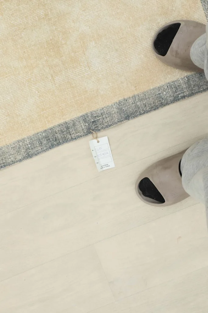 Overhead view of the rug with a size tag next to a person's feet for scale
