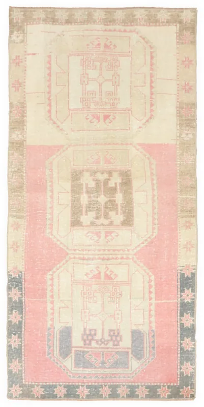 Full overhead view of a rose and ivory geometric Anatolian runner rug on a white background