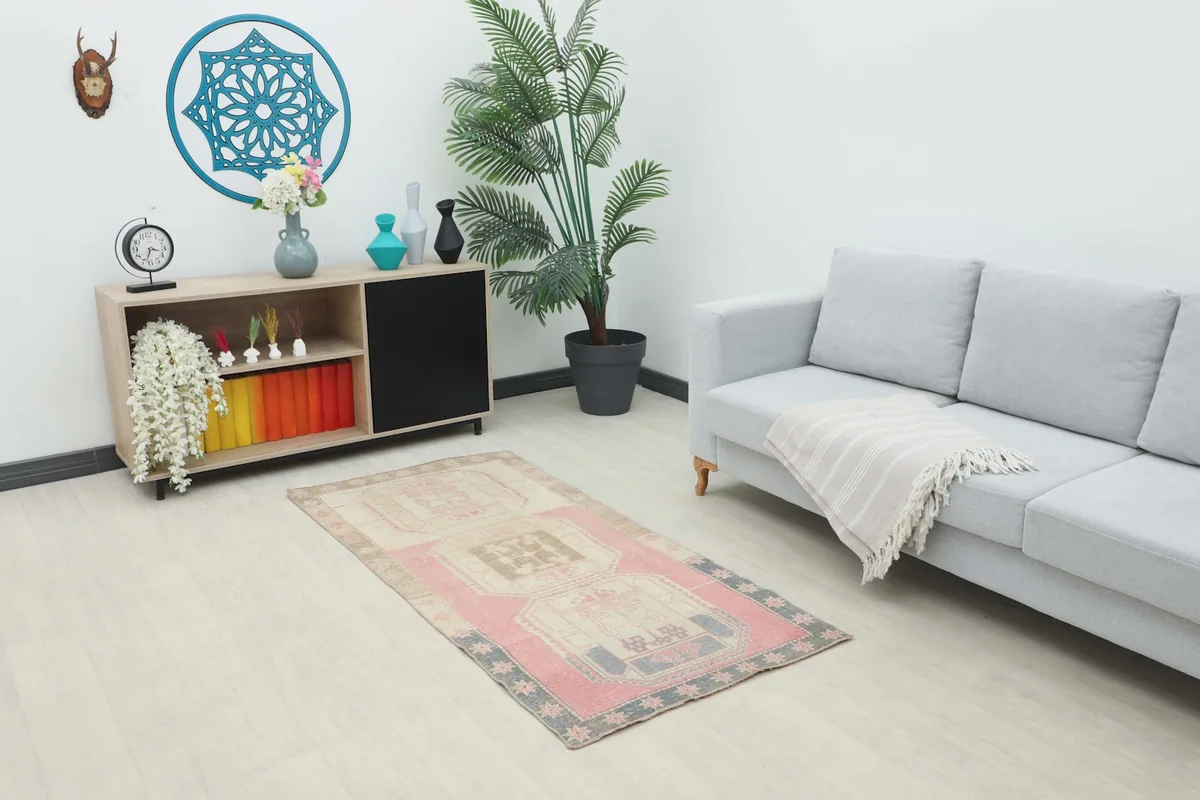 Rose and ivory vintage runner rug placed in a modern living space with a gray sofa and wooden cabinet