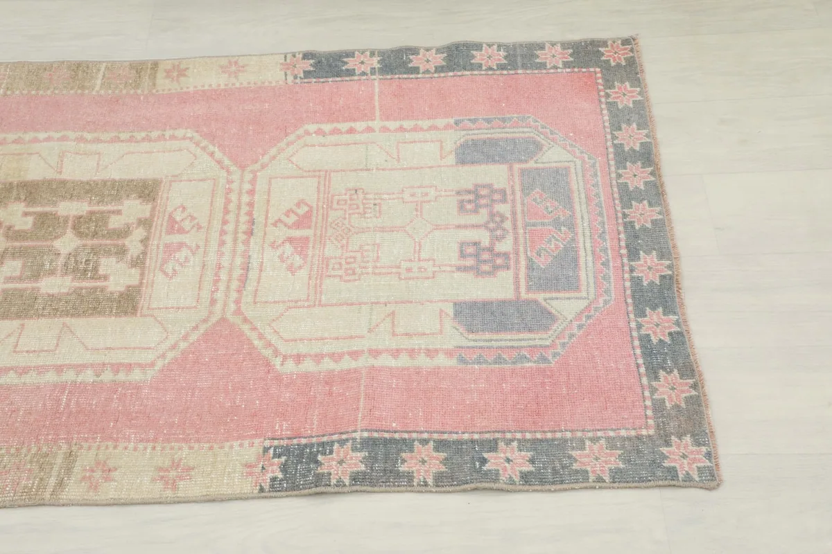 Close-up detail of the lower section of the rug showing rose, ivory, and gray geometric patterns
