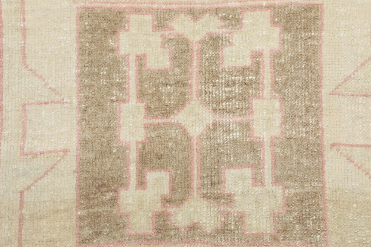 Extreme close-up of the central tan and ivory geometric motif within the rug