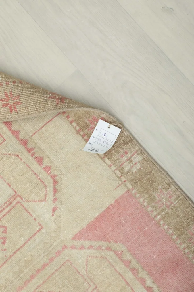 Close-up of the back of the rug with a tag, showing the hand-knotted cotton foundation