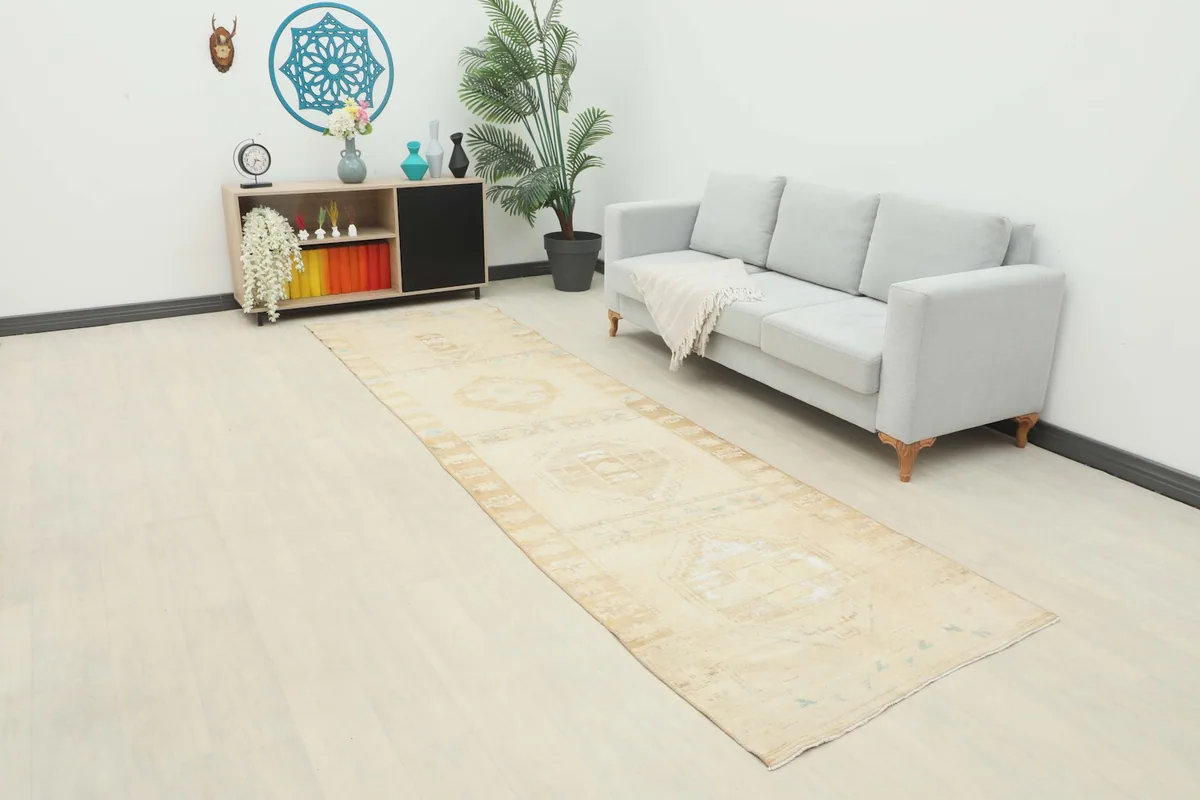 Long view of the beige runner rug laid out in a room with a light sofa and decor.