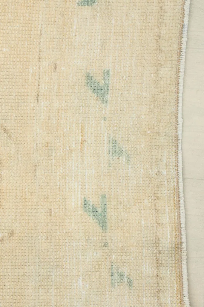 Detail of the rug's side edge and the subtle blue geometric accents along the field.