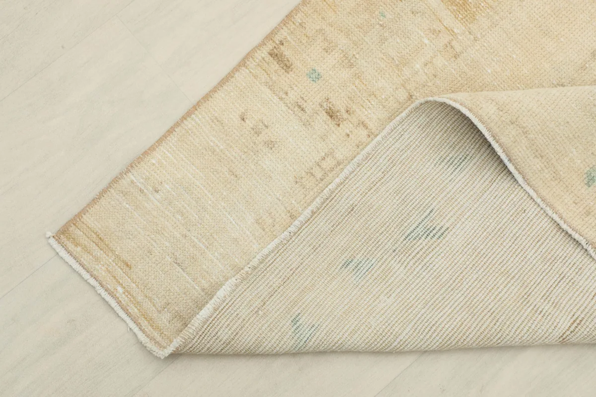 View of the rug's backside and its hand-knotted construction, folded over.