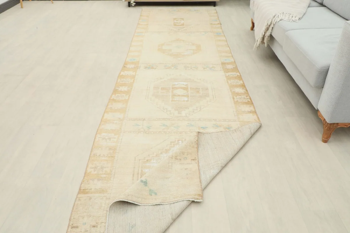 The runner rug with one end folded back, showing the cotton foundation and wool pile.