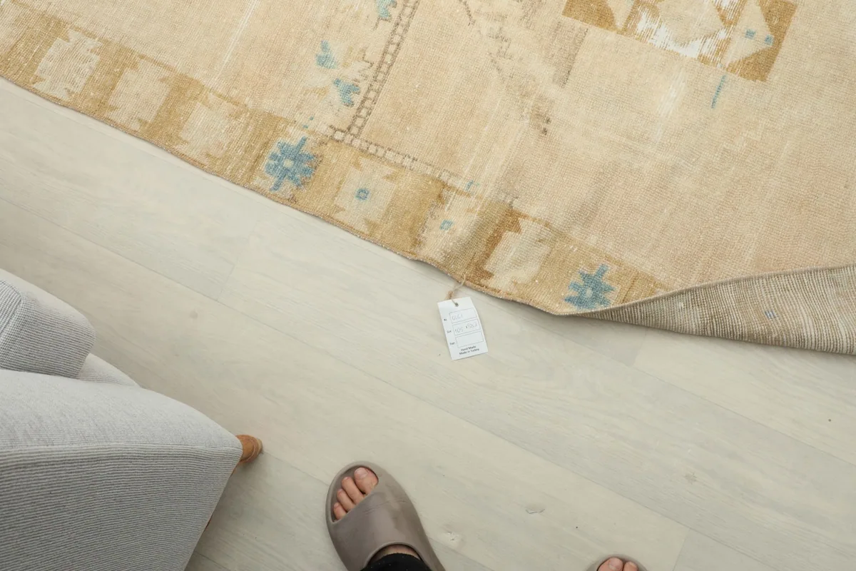 Top-down view of the rug's label and a person's feet, indicating scale.