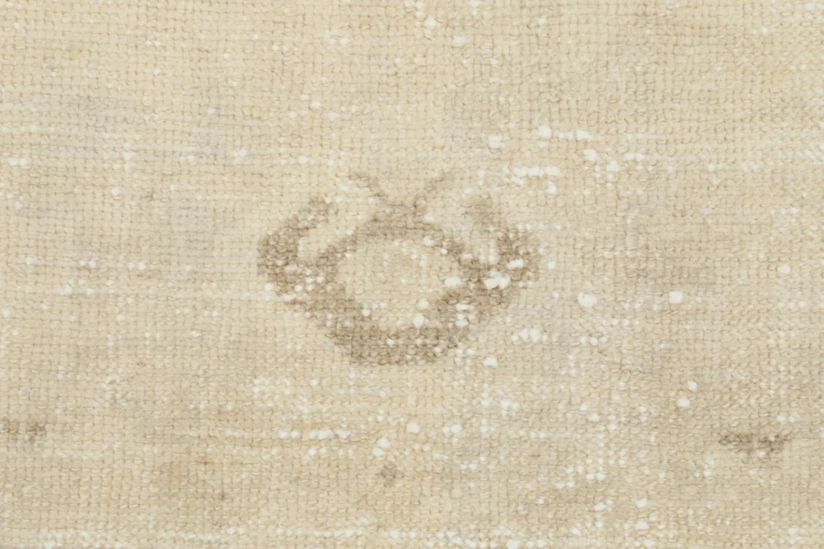 Close-up of the small, subtle geometric motif near one end of the vintage beige runner rug.