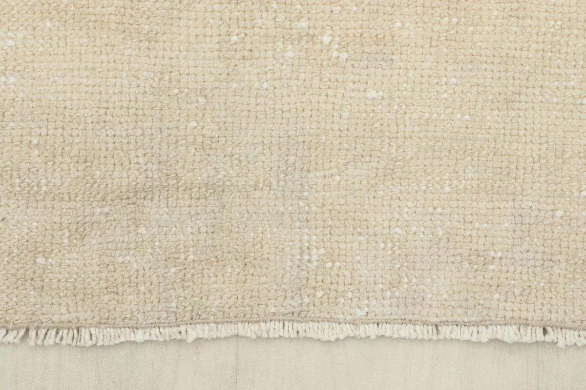 Close-up view of the low wool pile and the hand-knotted texture of the rug, with short fringes.