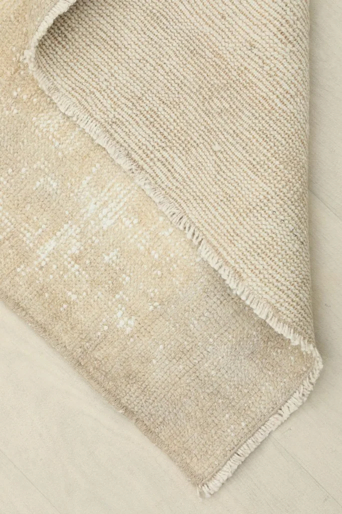 View of the back of the rug, showing the cotton foundation and the reverse of the hand-knotted wool pile.