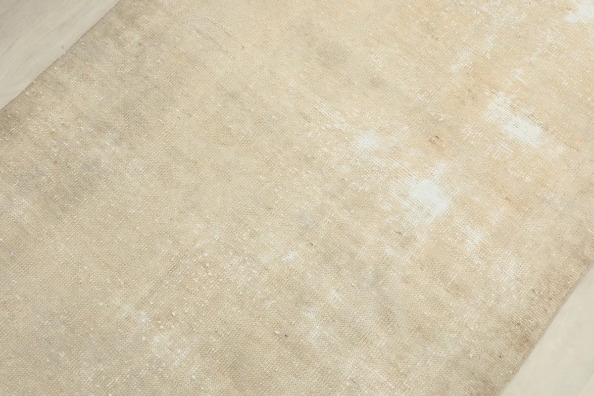 Overhead view showing the texture and color variation across the beige wool pile of the runner rug.