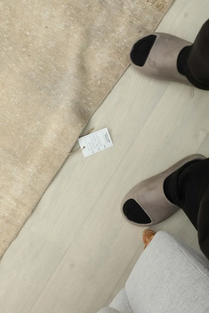Person's feet next to the rug, showing its scale and texture against a light wood floor.