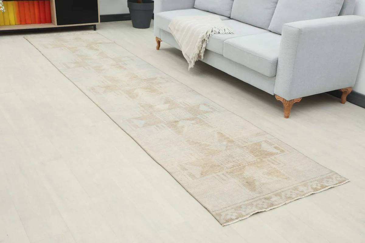 Angled view of the beige geometric runner rug extending from a sofa towards a cabinet