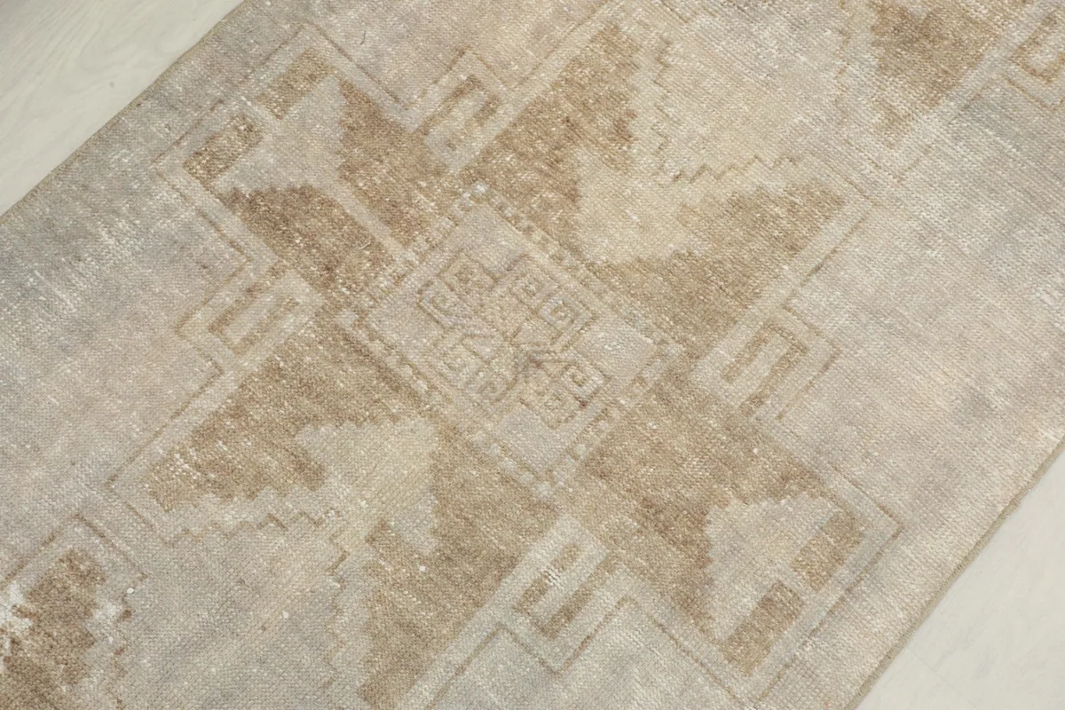 Detailed shot of a central tan geometric motif against the lighter beige field of the rug