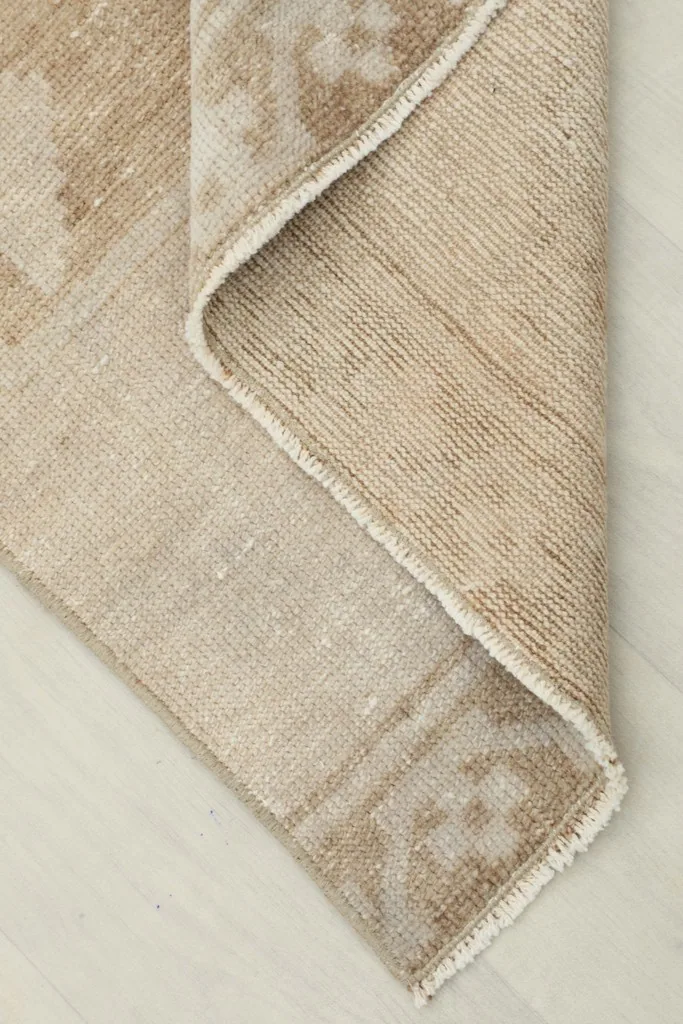 Corner of the rug folded to reveal the cotton foundation and the reverse side of the hand-knotted weave