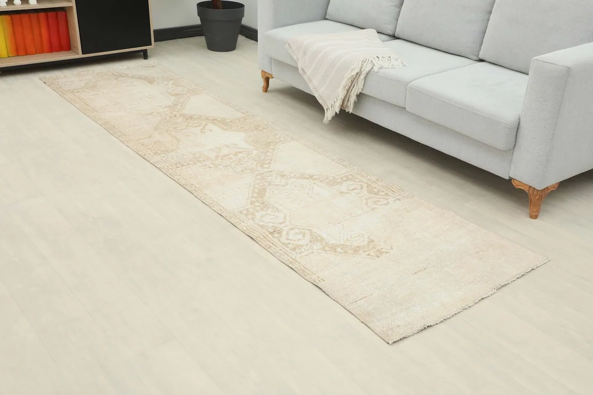 Angled view of the beige runner rug in a room, highlighting its length and muted tones