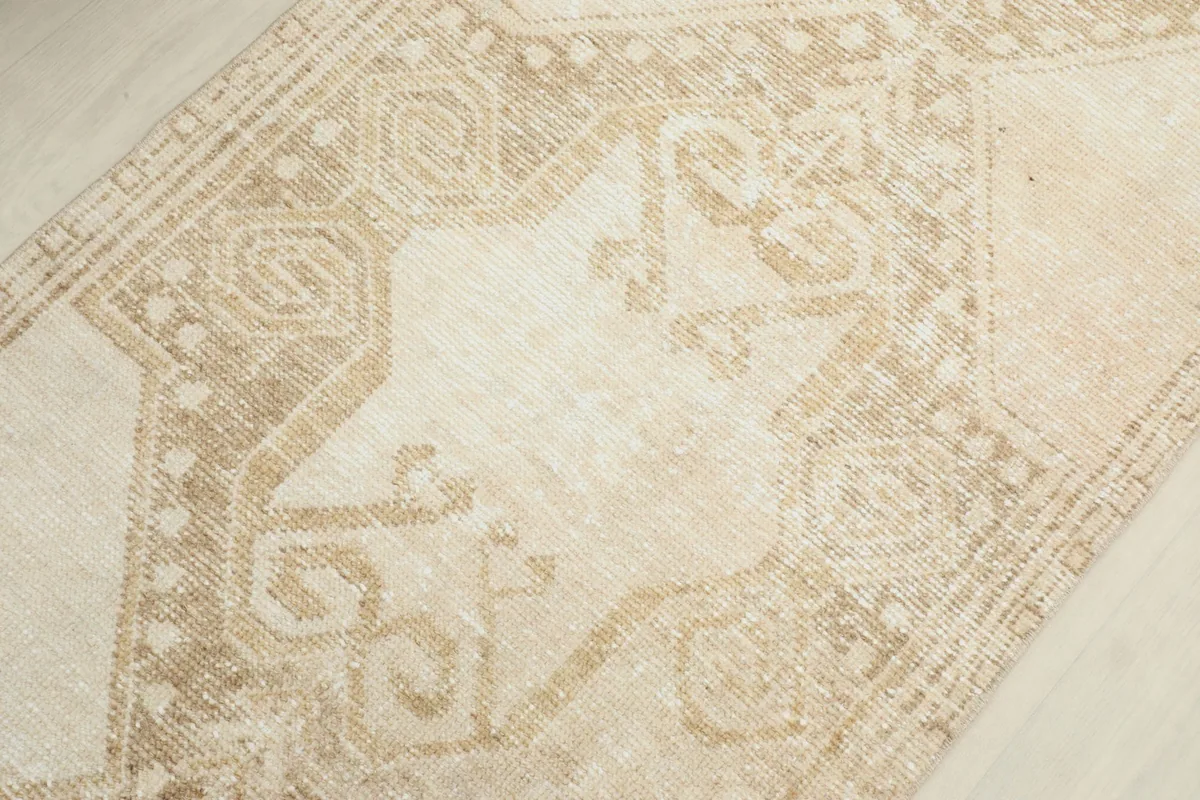 Detailed view of the hand-knotted wool pile and intricate, faded geometric designs