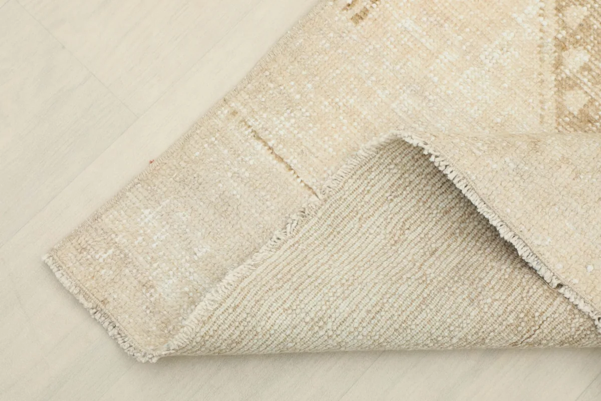 Corner of the rug folded to show the cotton foundation and hand-knotted construction