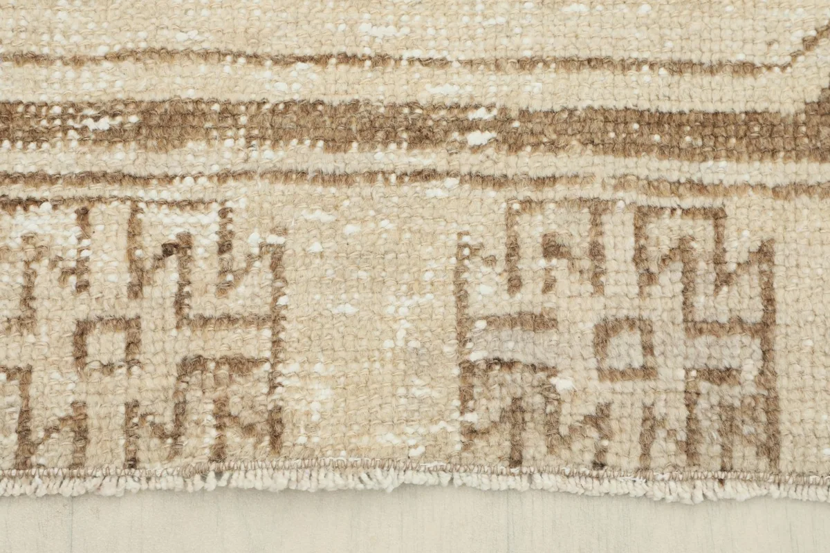 Detail of the end border with tribal patterns and short, natural fringes