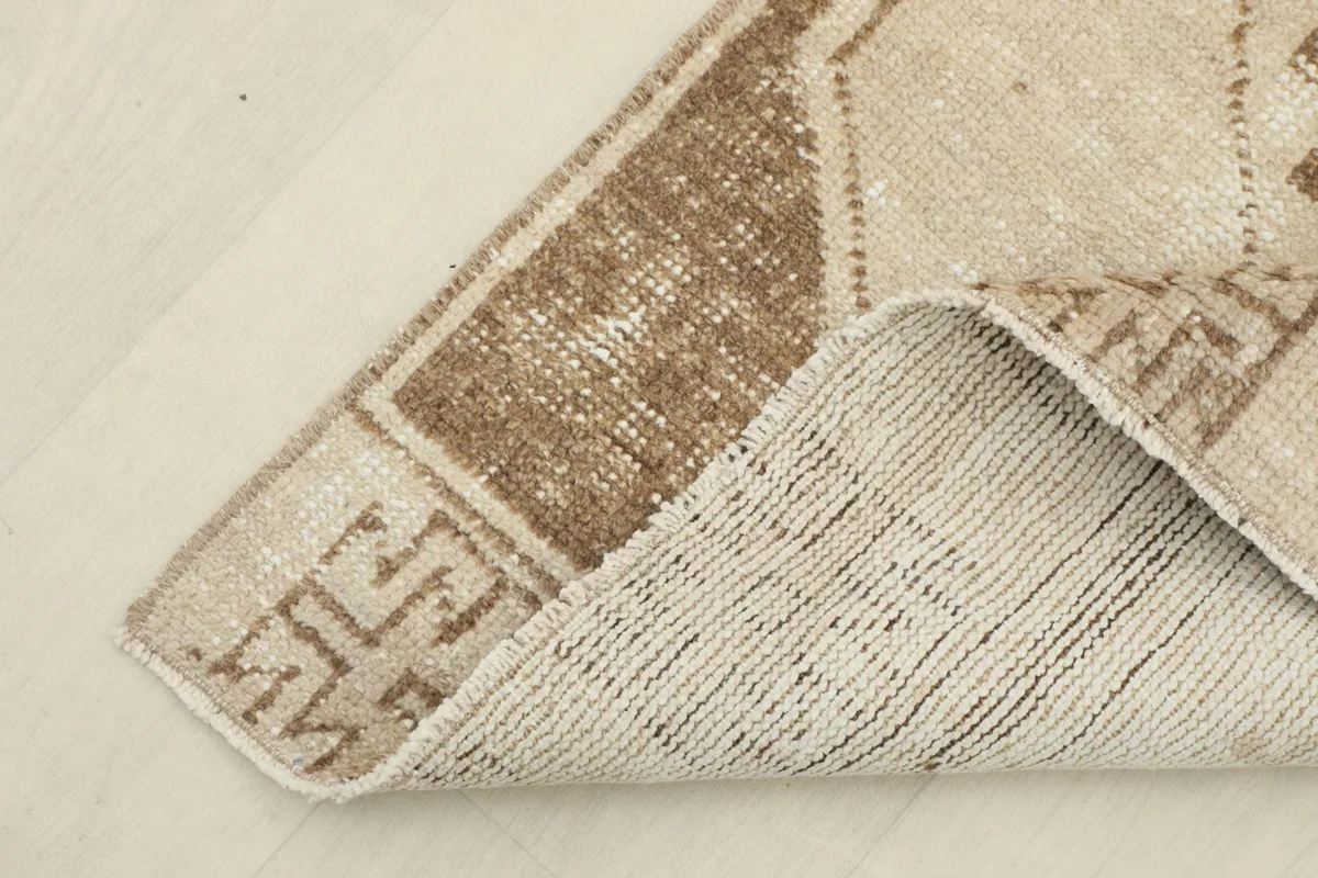 Corner of the runner rug folded to show the cotton foundation and hand-knotted reverse side