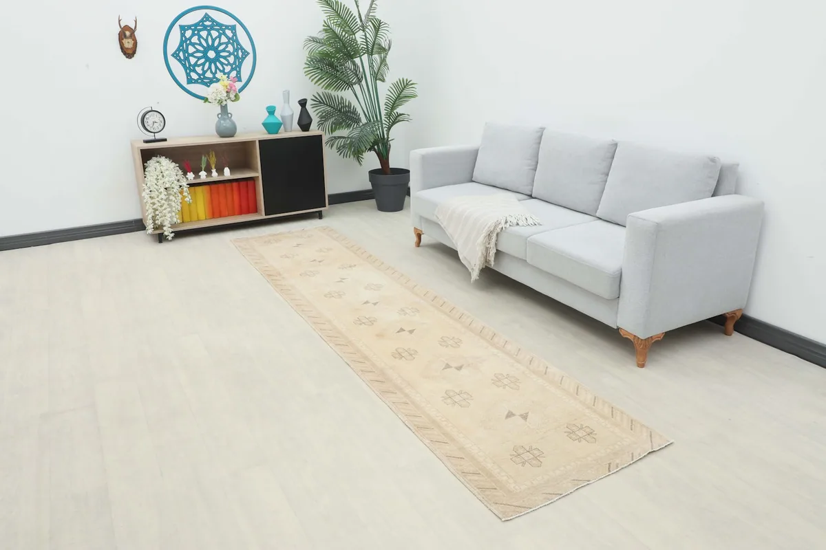 Ivory runner rug displayed in a room setting, extending from a console table towards a light gray sofa.