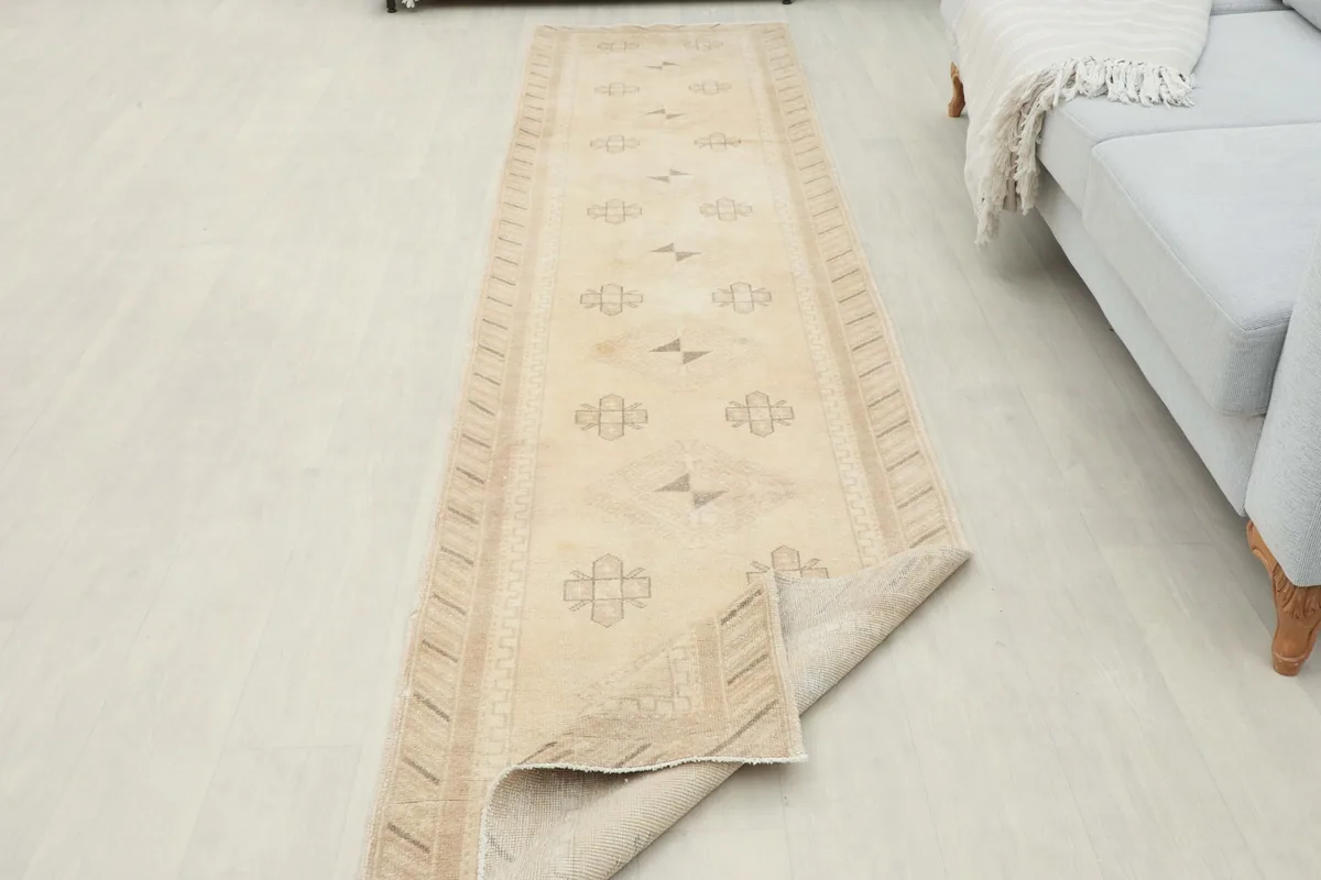 Long view of the ivory runner rug partially rolled, showing its full length in the room.