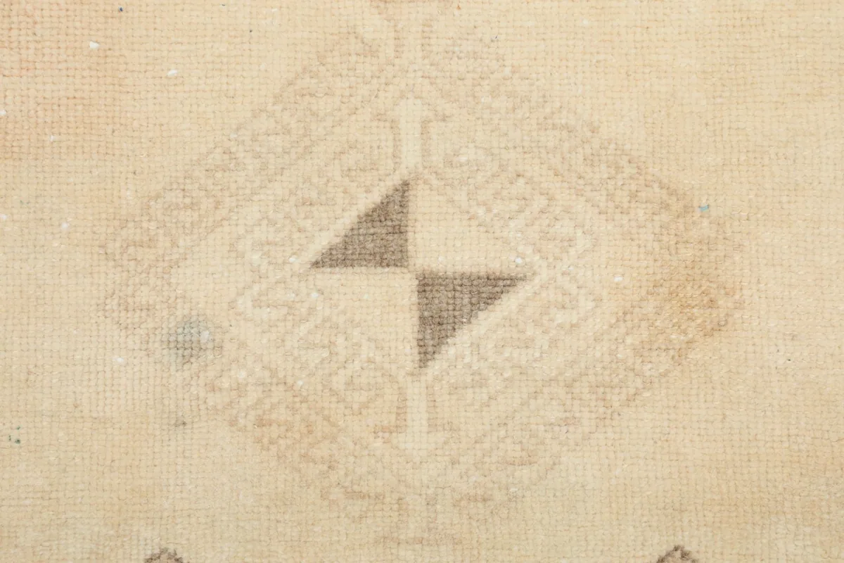 Macro detail of a specific diamond-shaped geometric motif within the ivory rug's pattern.