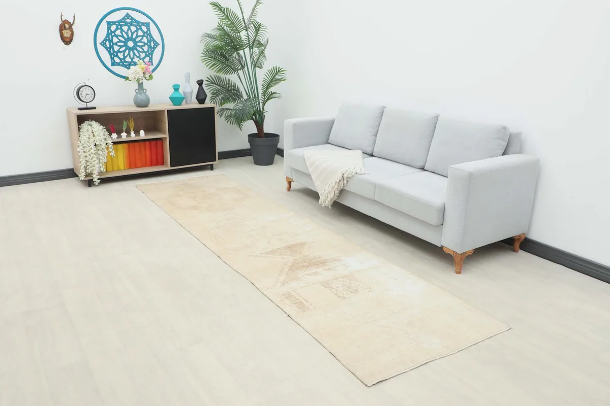 Beige Anatolian runner displayed in a modern living room setting next to a light gray sofa.