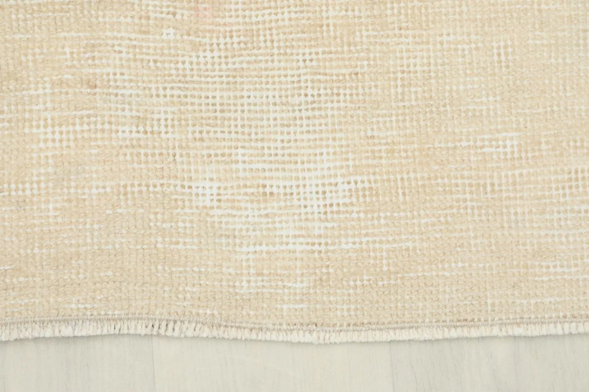 Close-up of the short, natural fringe on one end of the vintage beige runner.