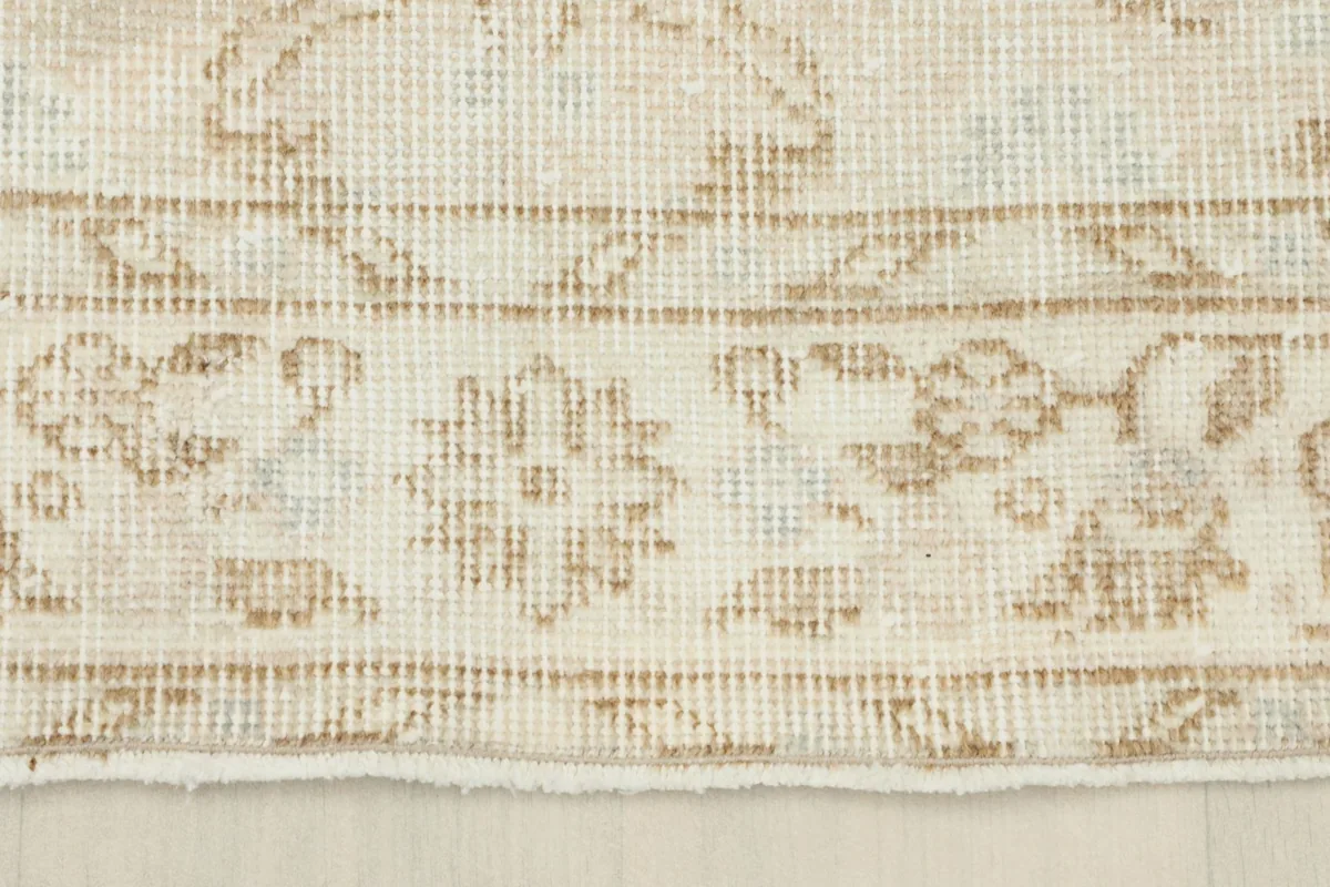 Close-up of the rug's border, displaying floral elements and the low pile.