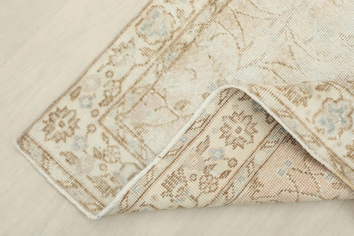 Corner of the rug folded back, showing the wool pile and cotton foundation.