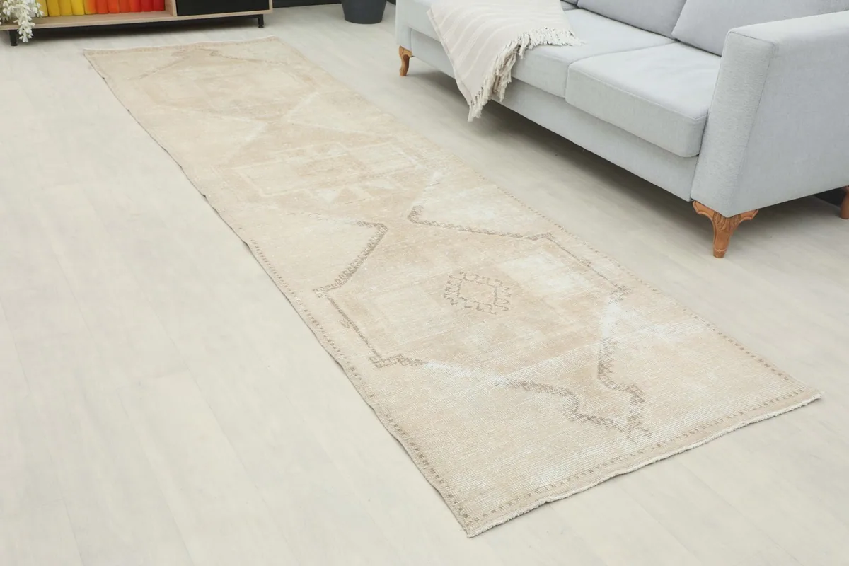 Beige geometric runner rug laid out in a modern living space with a light gray sofa