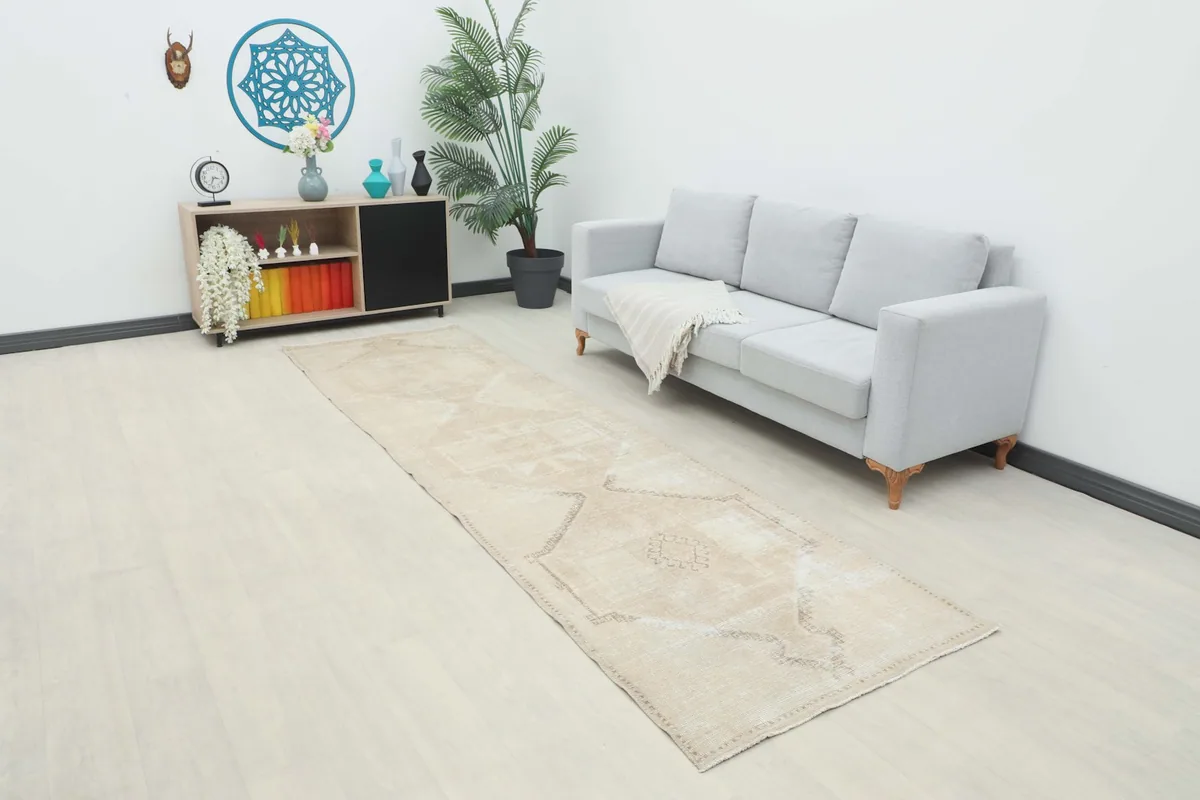 Long view of the beige runner rug in a room setting with a sofa and side cabinet