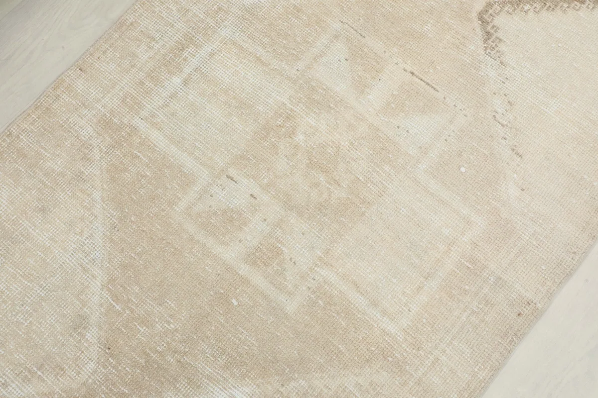 Detailed view of a central geometric motif in beige and tan on the vintage runner rug