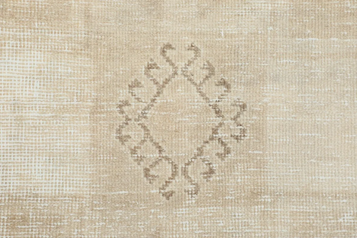 Close-up of a tribal-inspired diamond motif with subtle tan outlines on the beige rug
