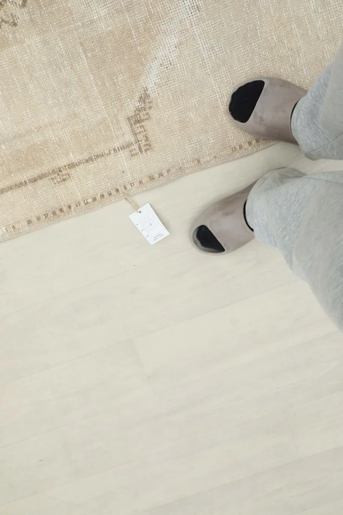 Overhead view of feet near the rug, showing the scale and a product tag