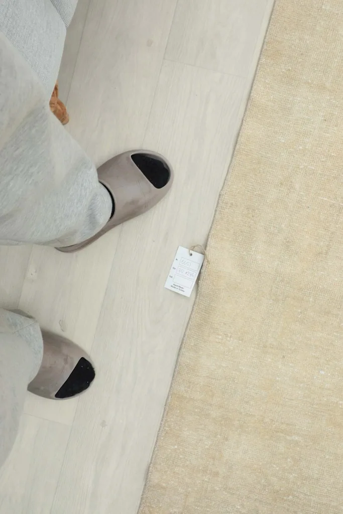 Feet in slippers next to the runner, showing its scale and a small product tag