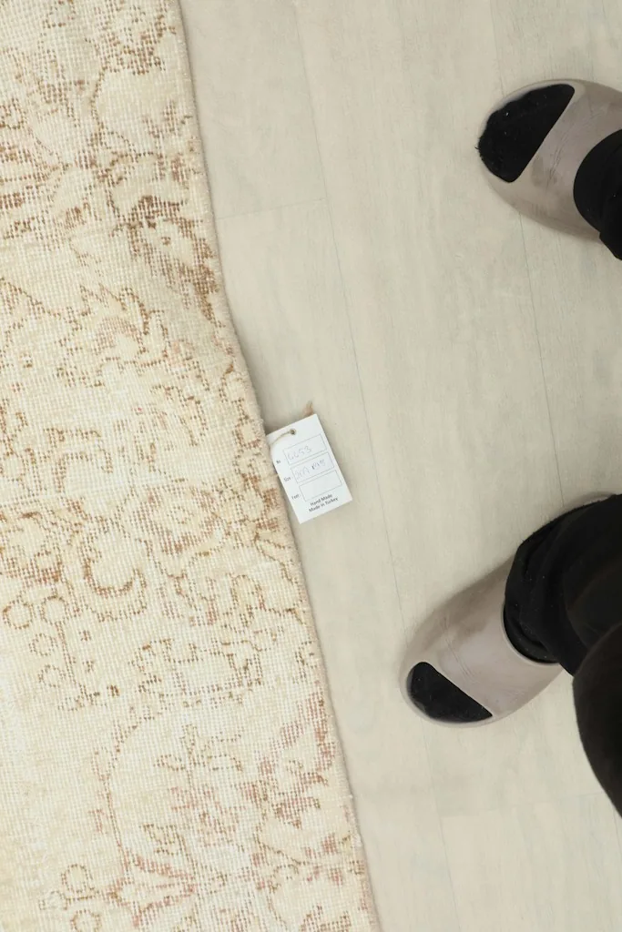 Overhead view of a tag on the rug, next to feet for scale