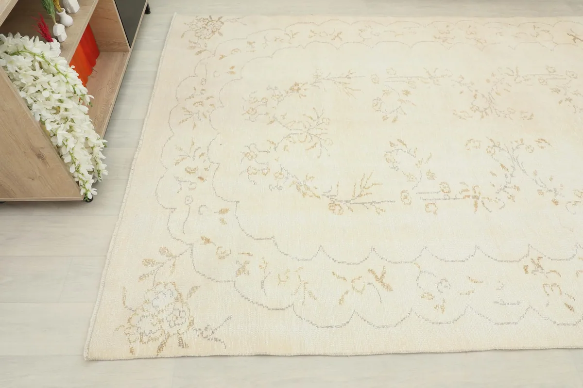 Another angle shot of the ivory rug showing the subtle floral motifs and distressed texture