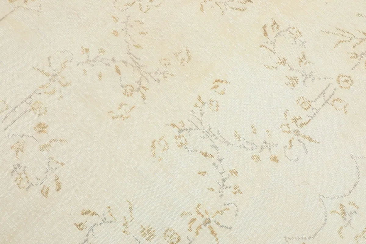 Detailed view of the beige and tan floral patterns on the ivory field of the rug
